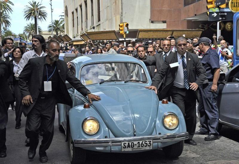 'Pepe' Mujica dirigindo seu Volkswagen 1987, depois de transmitir o cargo presidencial, em 2015, cercado de guarda-costas e seguido pela multidão