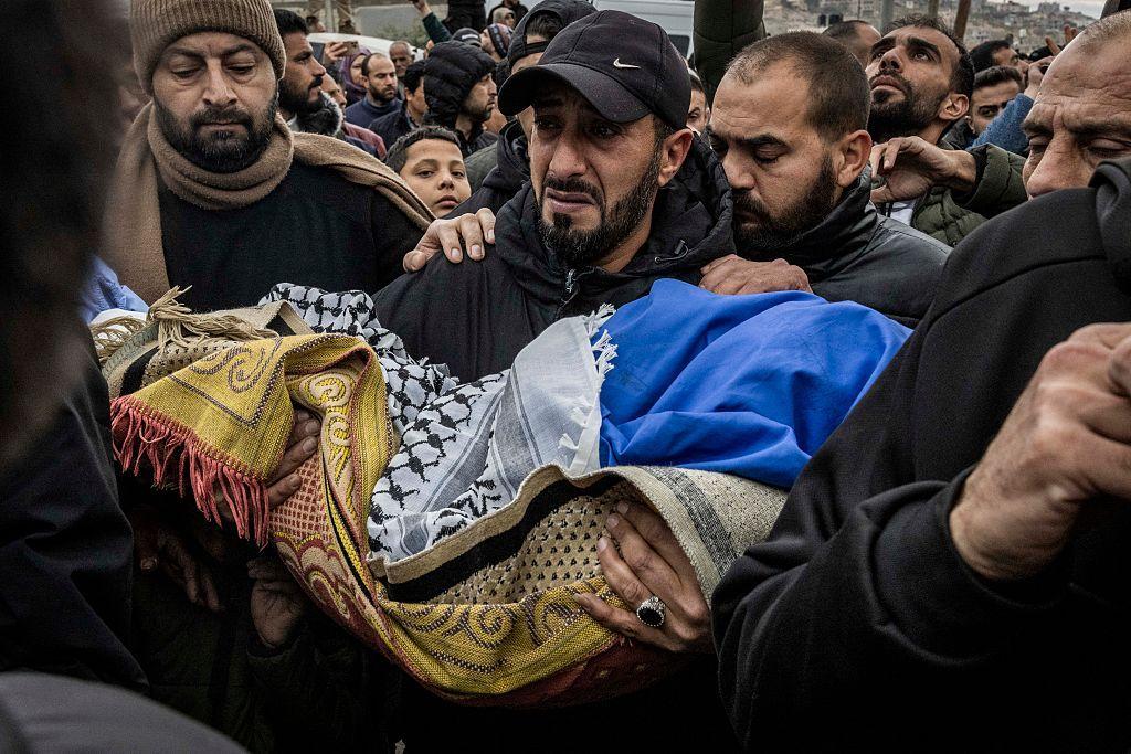 Un hombre carga el cuerpo de Mohammed Bani Odeh, de cinco años, durante el funeral de cuatro miembros de la misma familia muerta en manos de las fuerzas israelíes.