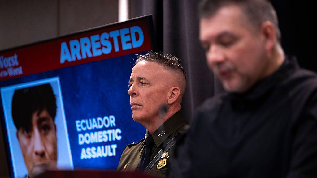 El comandante de la Patrulla Fronteriza, Gregory Bovino (C), observa mientras Marcos Charles, subdirector Ejecutivo de Operaciones de Cumplimiento y Deportación de ICE, habla durante una conferencia de prensa en la sede federal Bishop Henry Whipple el 22 de enero de 2026 en Mineápolis, Minesota.  (Foto por Stephen Maturen/Getty Images)