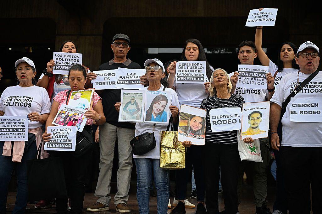 Familiares de presos políticos de pie y pegados en grupo. Llevan camisetas donde se lee "liberern a todos los presos políticos" y carteles donde pone "el rodeo es tortura", "Cierren el rodeo" y fotos de familiares. 