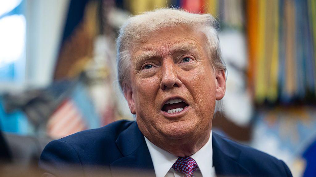 Trump, con la boca abierta, habla a los reporteros en el Despacho Oval. 