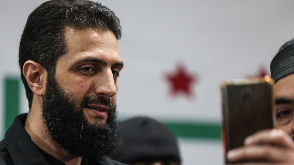 من تاتشر إلى أحمد الشرع: كيف يغيّر السياسيون صورتهم؟ ولماذا؟ 4 أبو محمد الجولاني، زعيم هيئة تحرير الشام، يلتقط صورة سيلفي خلال مؤتمر صحفي في منطقة معبر باب الهوى شمال سوريا، مساء 12 مارس 2024.