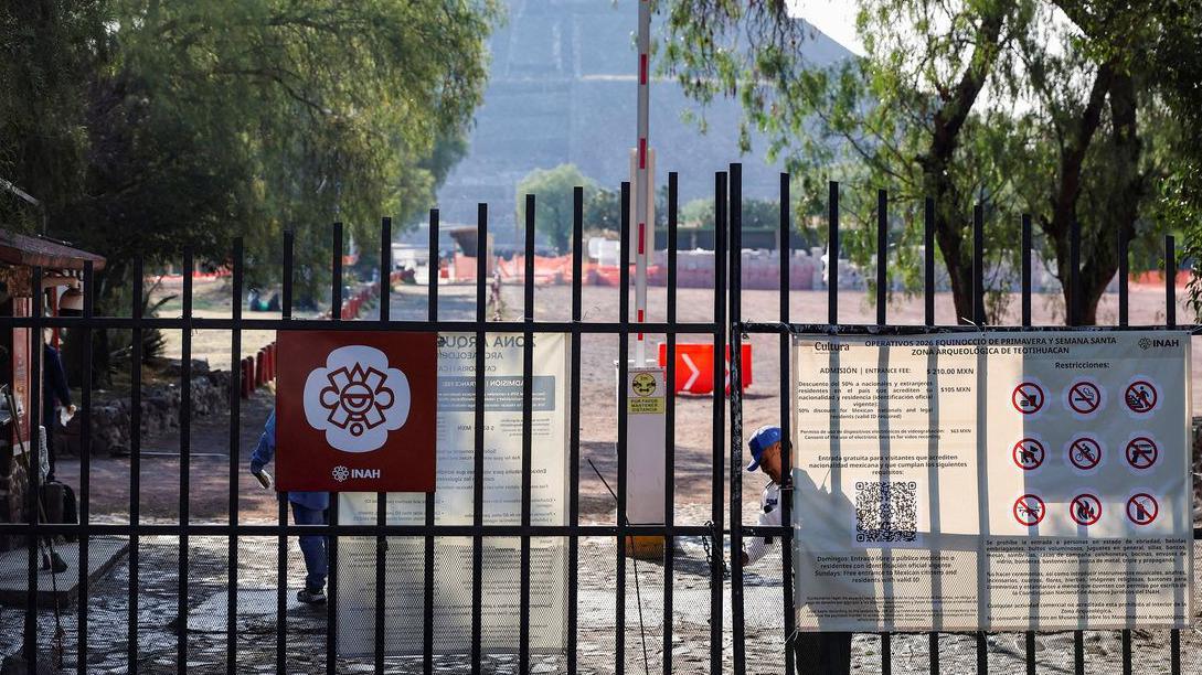 Zatvoreni prilaz istorijskom lokalitetu u Meksiku, muškarac u beloj unifromi, na ogradi nekoliko plakata