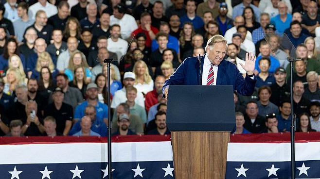 Mike Rogers saluda al público desde un atril en un evento de campaña en Michigan.