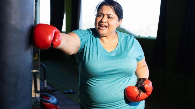 Una mujer con guantes de boxeo lanza un puñetazo.