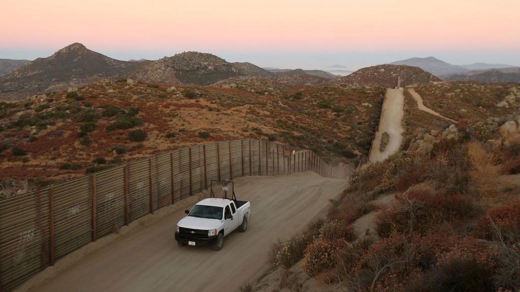 Un vehículo de la patrulla policial circula cerca del muro que divide la frontera entre México y EE.UU.
