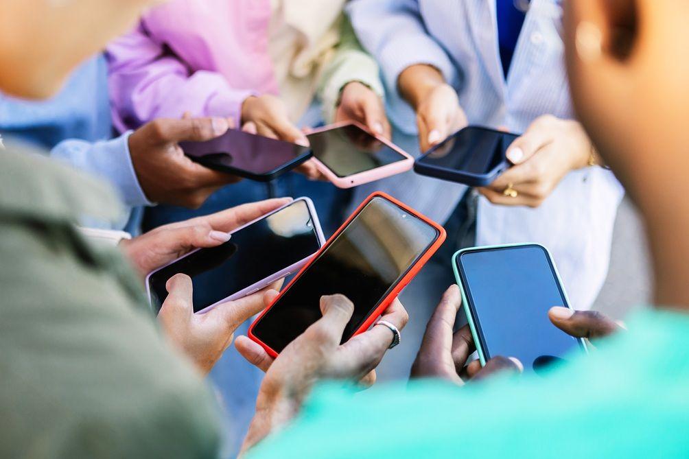 Pessoas n&atilde;o identificadas seguram celulares em local p&uacute;blico