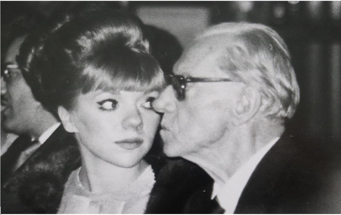 Una imagen cerrada en blanco y negro de una joven mujer con un peinado elegante y un hombre mayor de perfil con anteojos