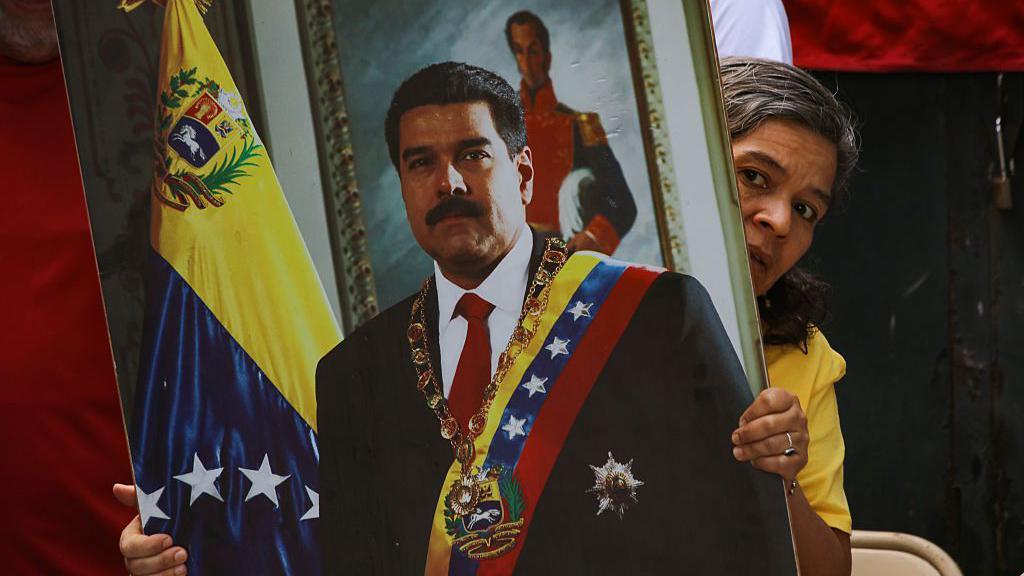 سيدة تحمل صورة رسمية لمادورو