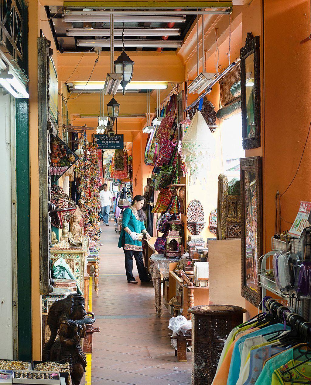 Una mujer pasea por una galería, que deja parte de la acera techada y donde los comercios exhiben sus productos.