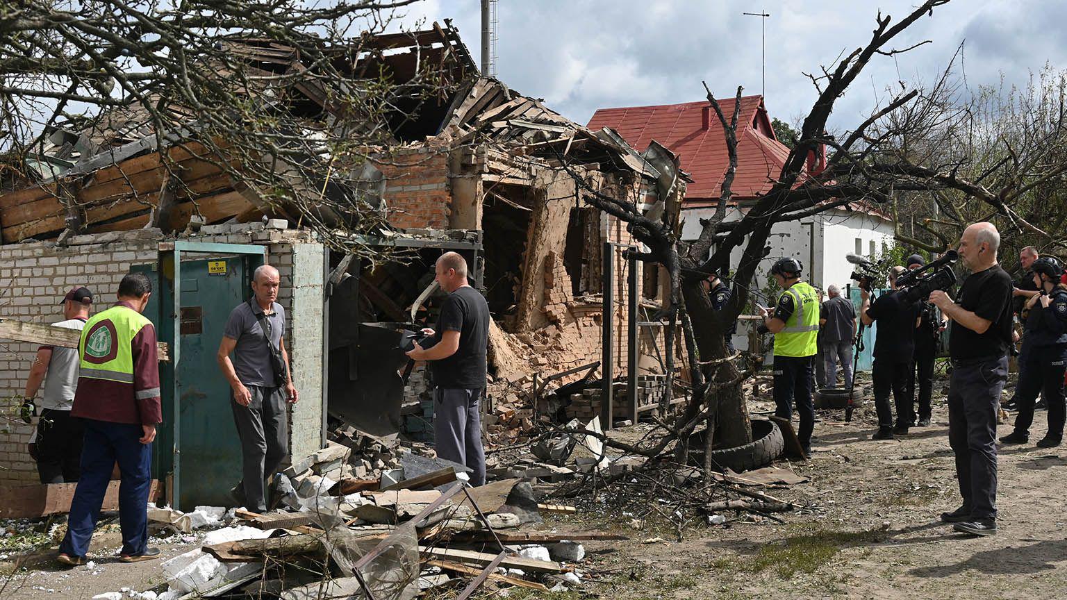 Uma casa destru&iacute;da por um ataque a&eacute;reo russo na Ucr&acirc;nia. Pessoas est&atilde;o ao redor do im&oacute;vel em ru&iacute;nas