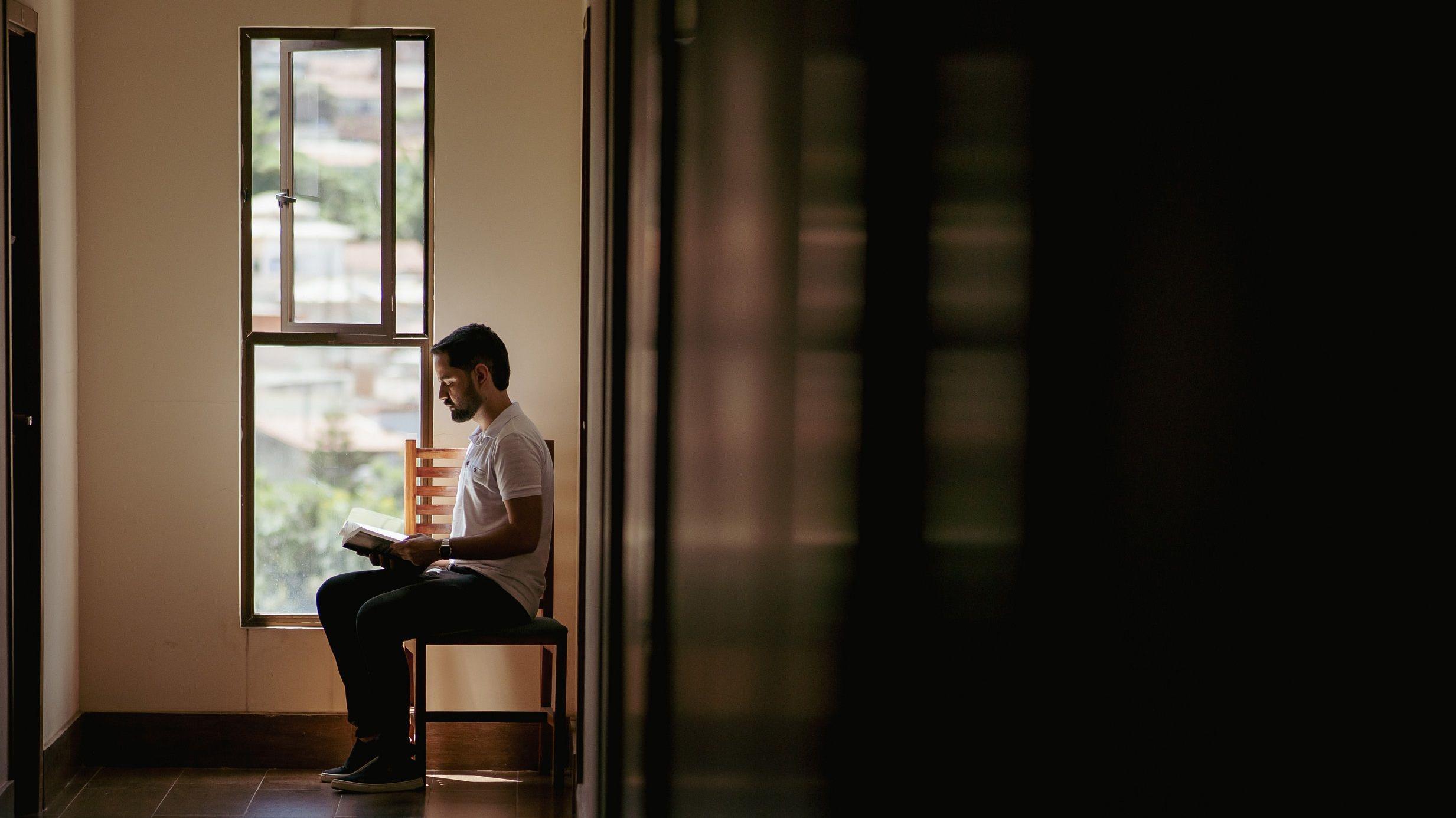 Kaik Ribas lendro um livro sentado de lado numa cadeira