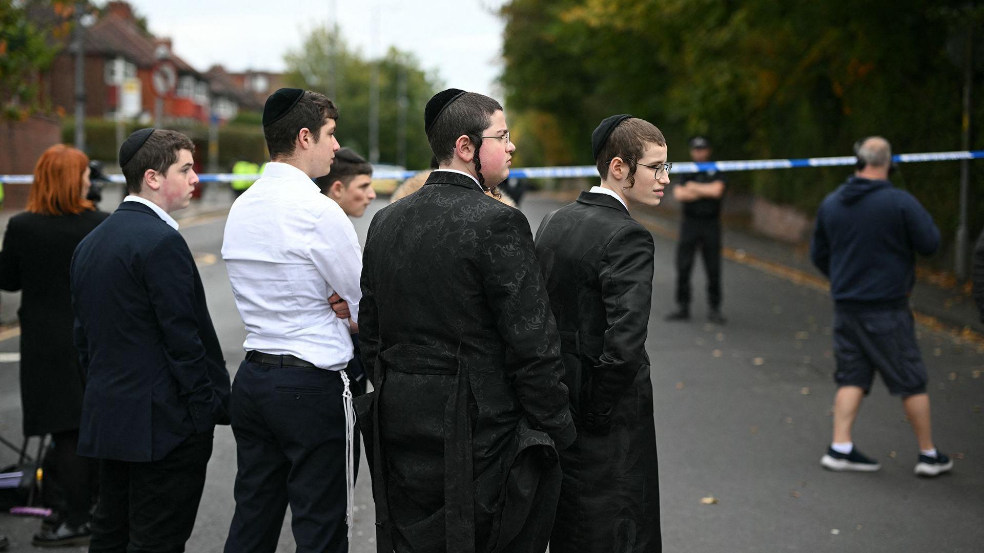 2025년 10월 2일, 맨체스터 북부 크럼솔에 위치한 히튼 파크 유대교 회당 인근에서 지역 주민들이 경찰 차단선 근처에 서 있는 모습
