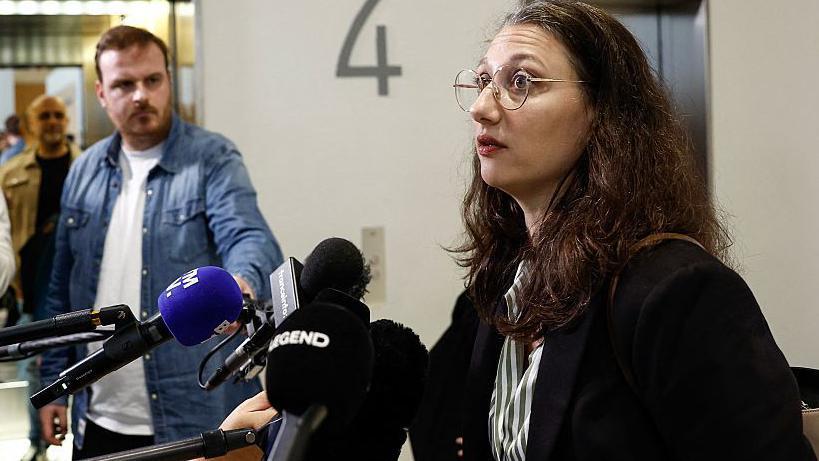 žena u tamnoj odeći i sa naočarima daje izjavu novinarima