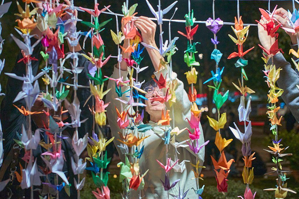 2025年11月18日，一名男子悼念宏福苑大火，正在掛上紙鶴。