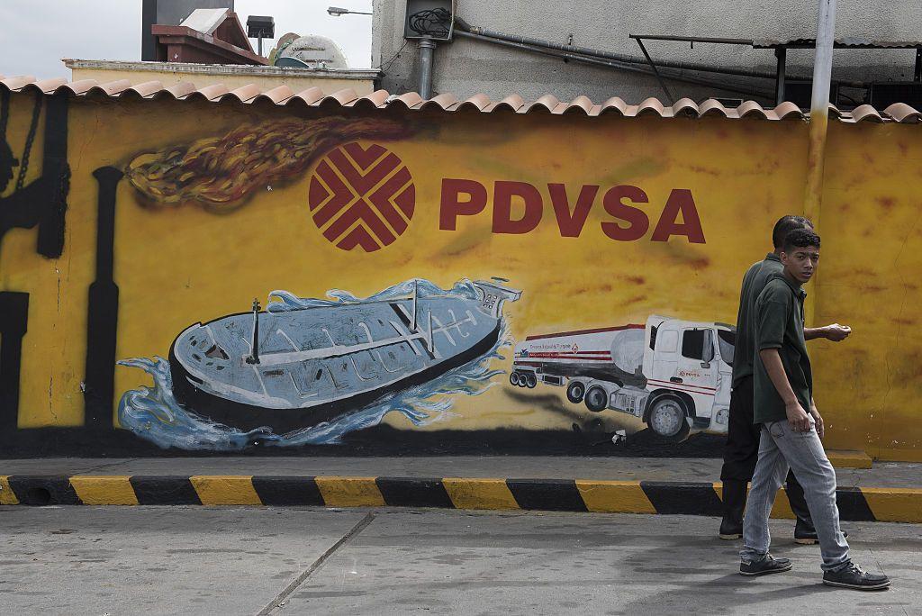 Pedestres caminham em frente a um mural da Petróleos de Venezuela SA (PDVSA) em Caracas, Venezuela, em 2015