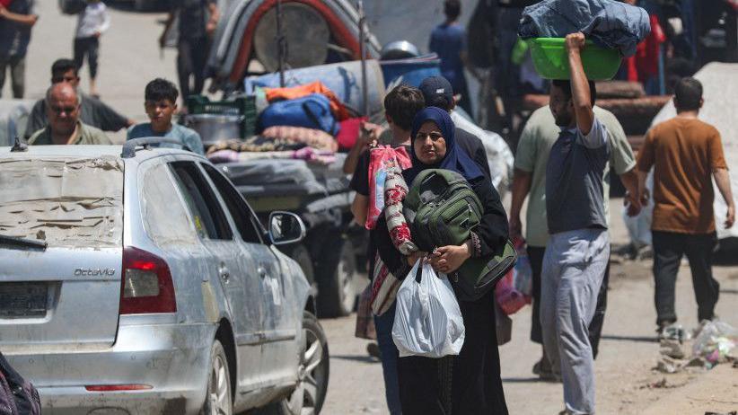 أنباء عن تغير في موقف حماس، وتحذيرات من كارثة إنسانية بسبب إخلاء غزة 1 فلسطينيون يحملون أمتعتهم ويسيرون يجانب سيارات مدمرة في قطاع غزة