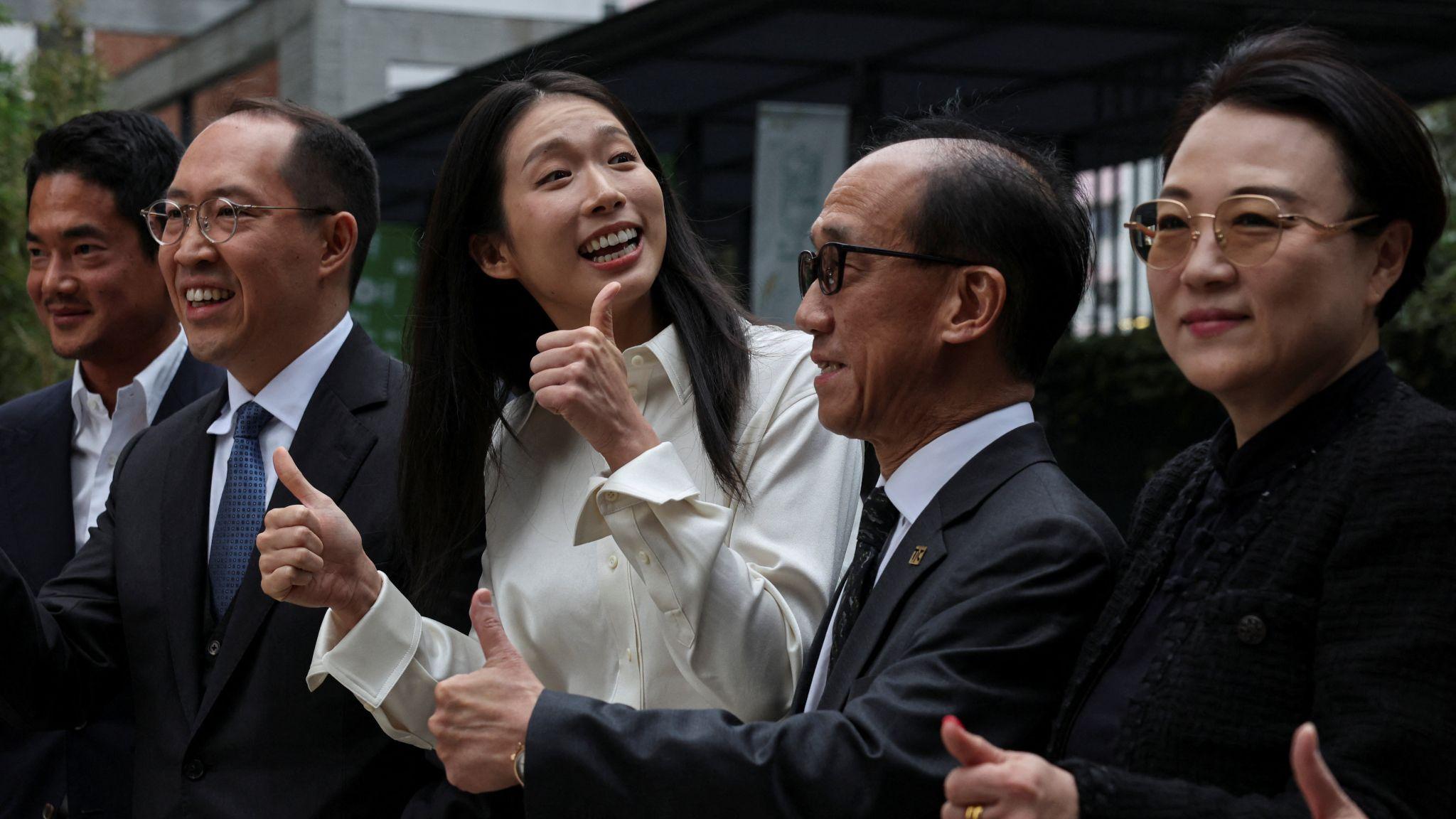 身穿白色襯衫的江旻憓（中）在香港北角出席參選發佈會時與陪同站台的商界高層人物向媒體記者展露笑容並豎起拇指（3/11/2025）