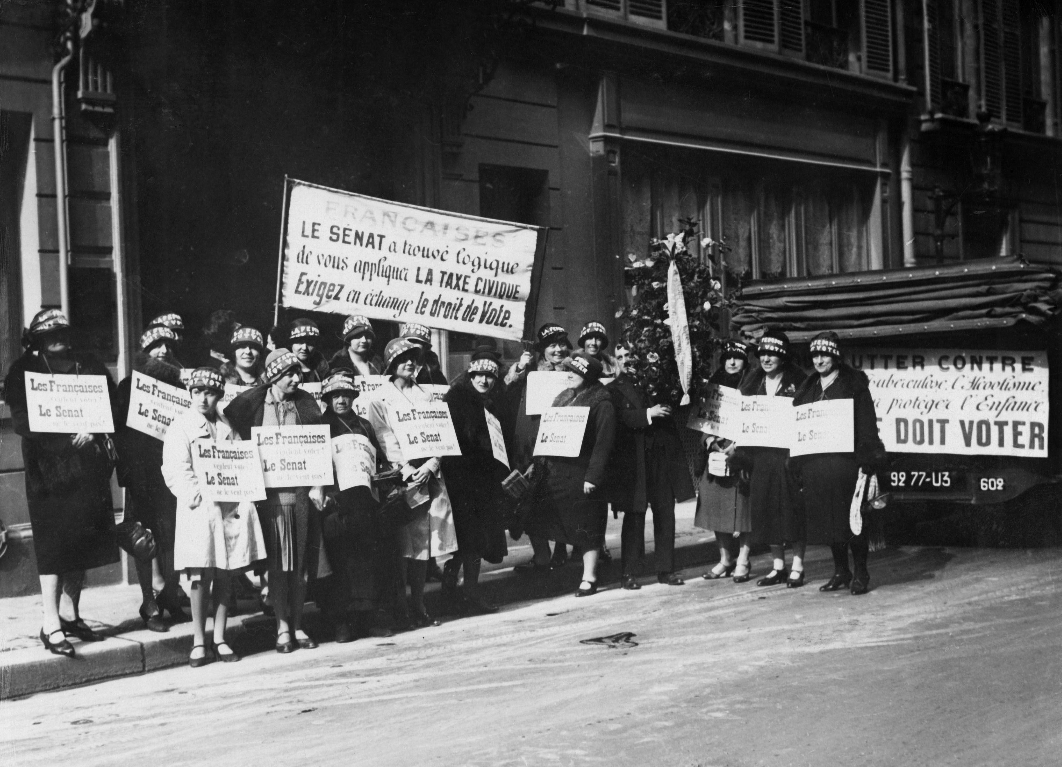 Una veintena de mujeres sostiene pancartas en francés durante las campañas sufragistas por el derecho al voto femenino en Francia en 1930.
