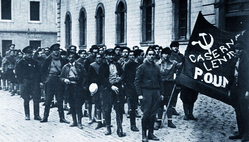 ميليشيا حزب العمال الماركسي الموحد تحرس مقر الحزب في برشلونة عام 1936، وفي الخلفية يقف الكاتب البريطاني جورج أورويل