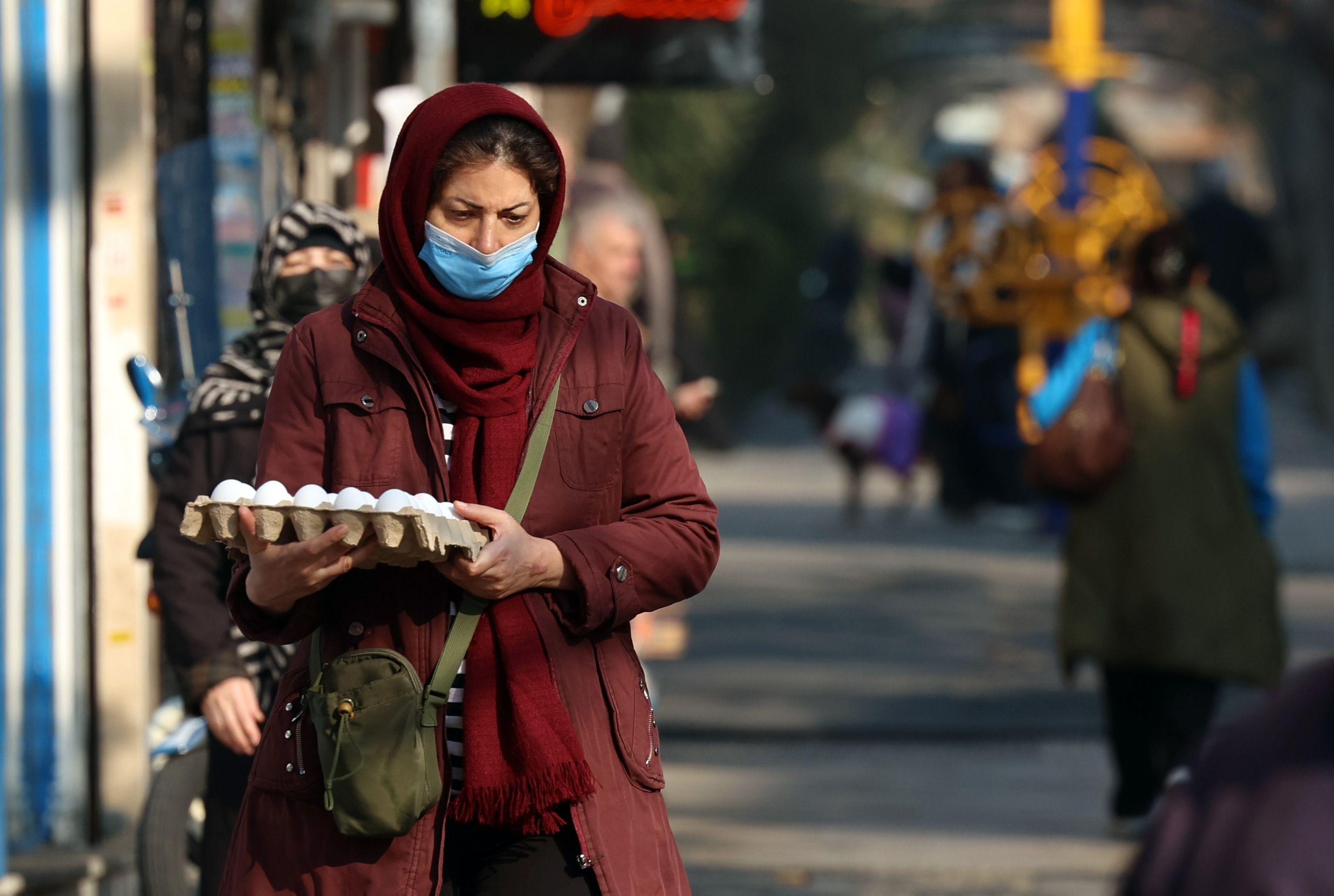 Una mujer iraní camina con un cartón de huevos en la mano por una calle de Teherán. 