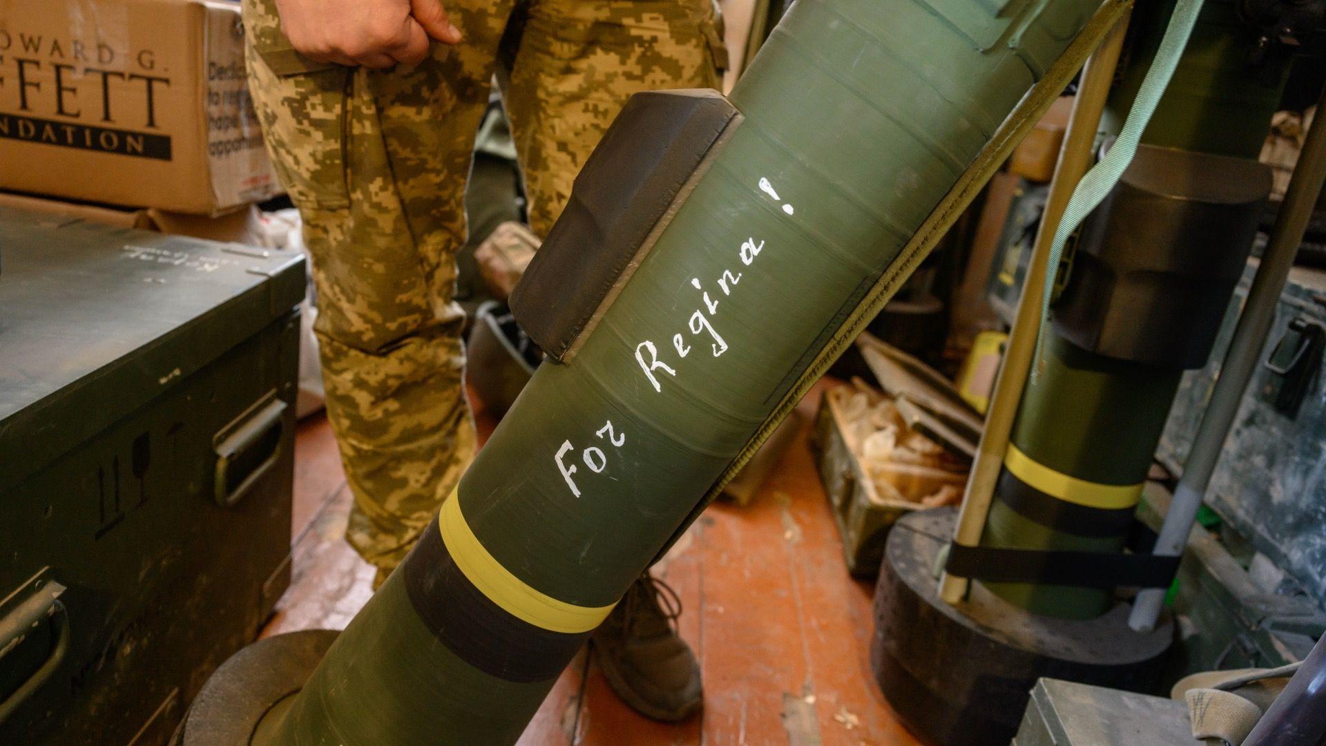 Zamrznuta ruska imovina: Šta hoće EU i zašto se Belgija protivi 8 Zelena raketa sa natpisom „Za Reginu!“ belom bojom. Raketa je na postolju na podu unutar sobe, a iza nje su noge vojnika u kamuflažnim pantalonama.