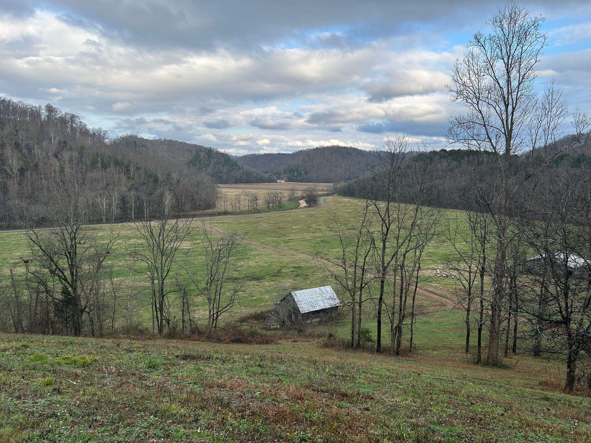 Un granero en unas colinas con árboles. 
