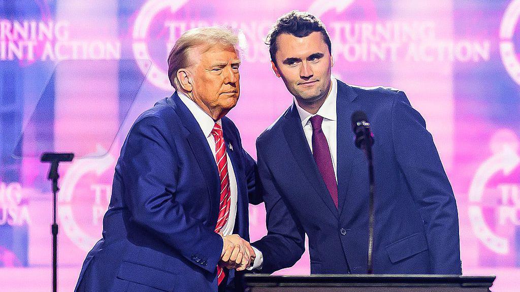 Kirk estrechándole la mano a Trump.