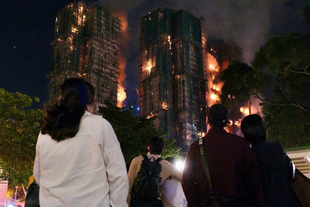 Varias personas miran hacia edificios incendiados en Hong Kong