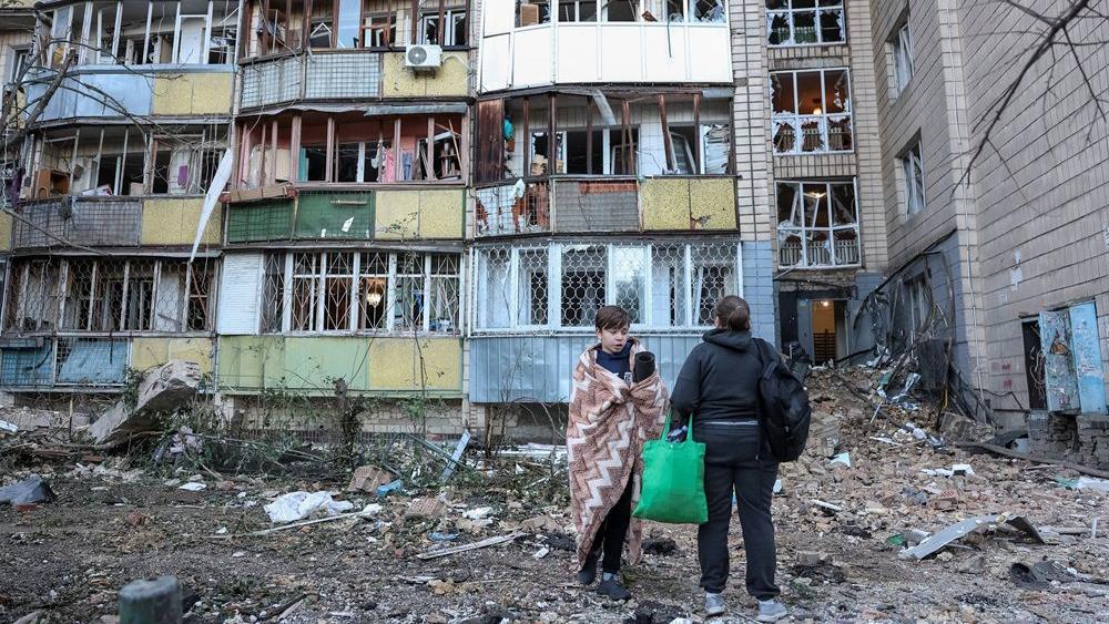napad na kijev, ljudi stoje ispred jedne od pogođenih zgrada u Kijevu