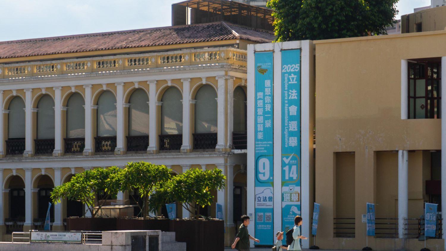 澳門塔石廣場，三名市民經過選舉直幡。