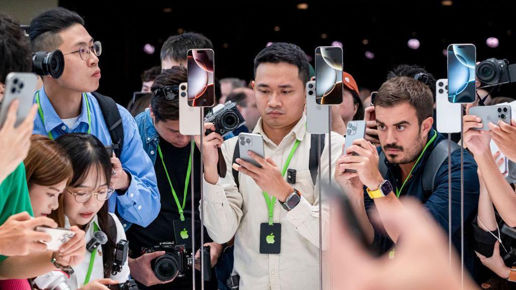 Una multitud fotografía con cámaras y iPhones las que parecen ser las versiones más recientes del iPhone de Apple
