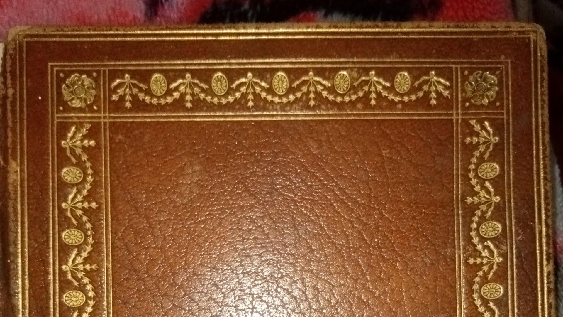The exterior of a leather-bound notebook. The cover is dark and features a golden design around the border.
