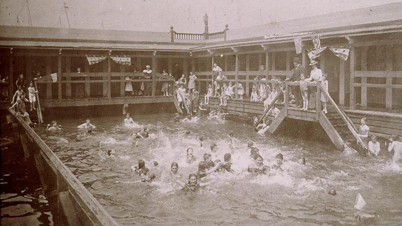 Imagem antiga de pessoas nadando em uma piscina coletiva