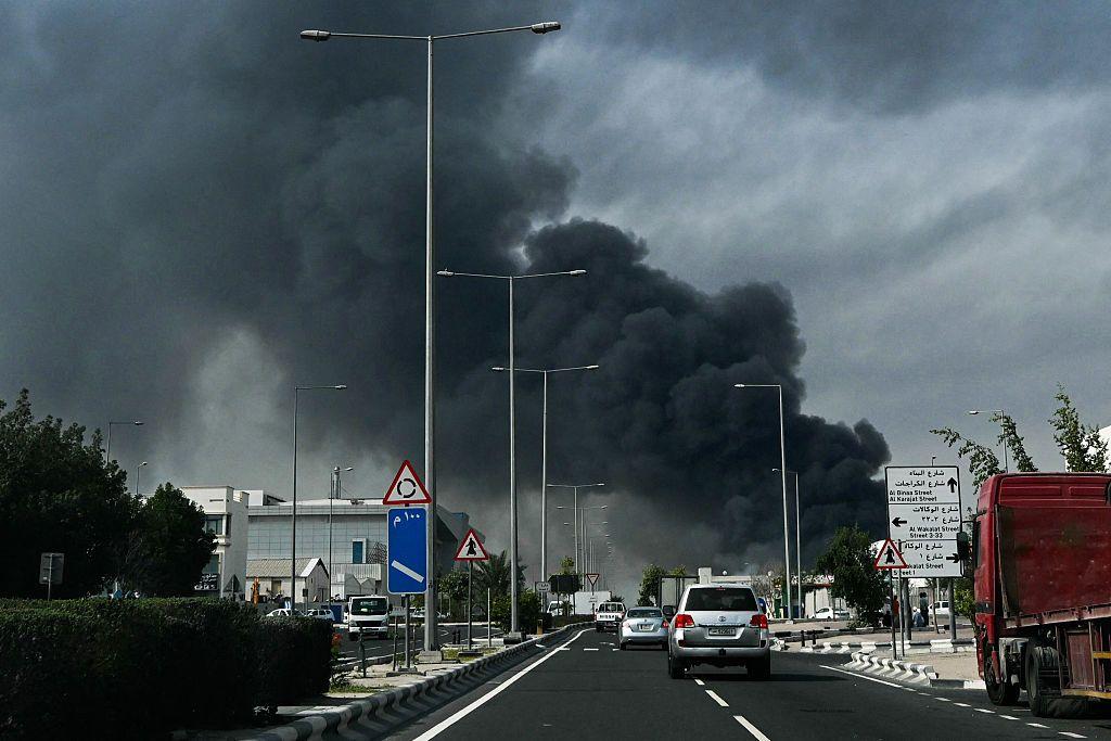 Uma espessa fuma&ccedil;a cinza-escura sobe ao fundo de uma rodovia ap&oacute;s um ataque iraniano relatado no distrito industrial de Doha