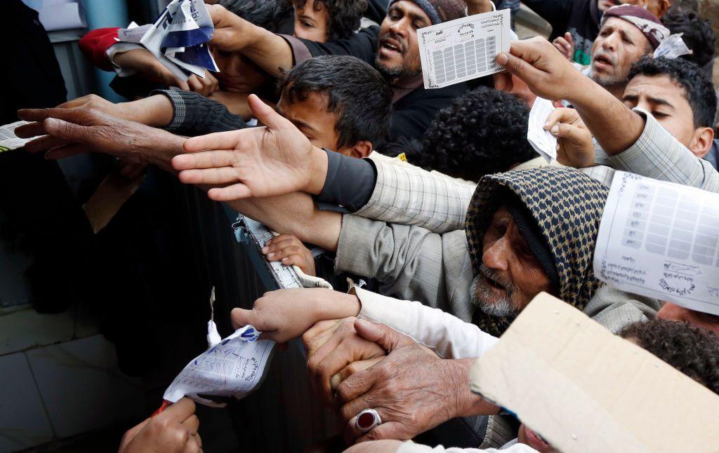 Una multitud se agolpa y estira sus brazos sujetando papeles en Yemen.