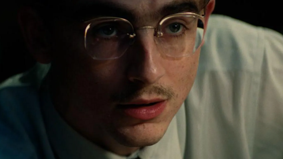 Primer plano de Timothée Chalamet, caracterizado como la estrella del tenis de mesa Mary Reisman, en una escena de Marty Supreme.