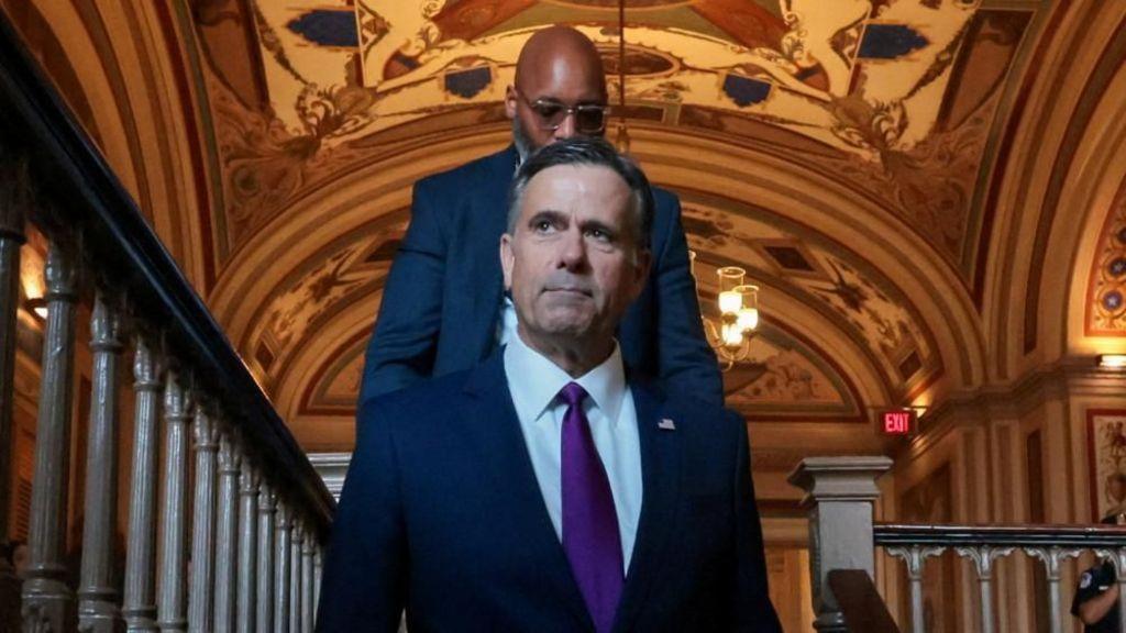 El director de la CIA, John Ratcliffe, con un hombre caminando detrás de él