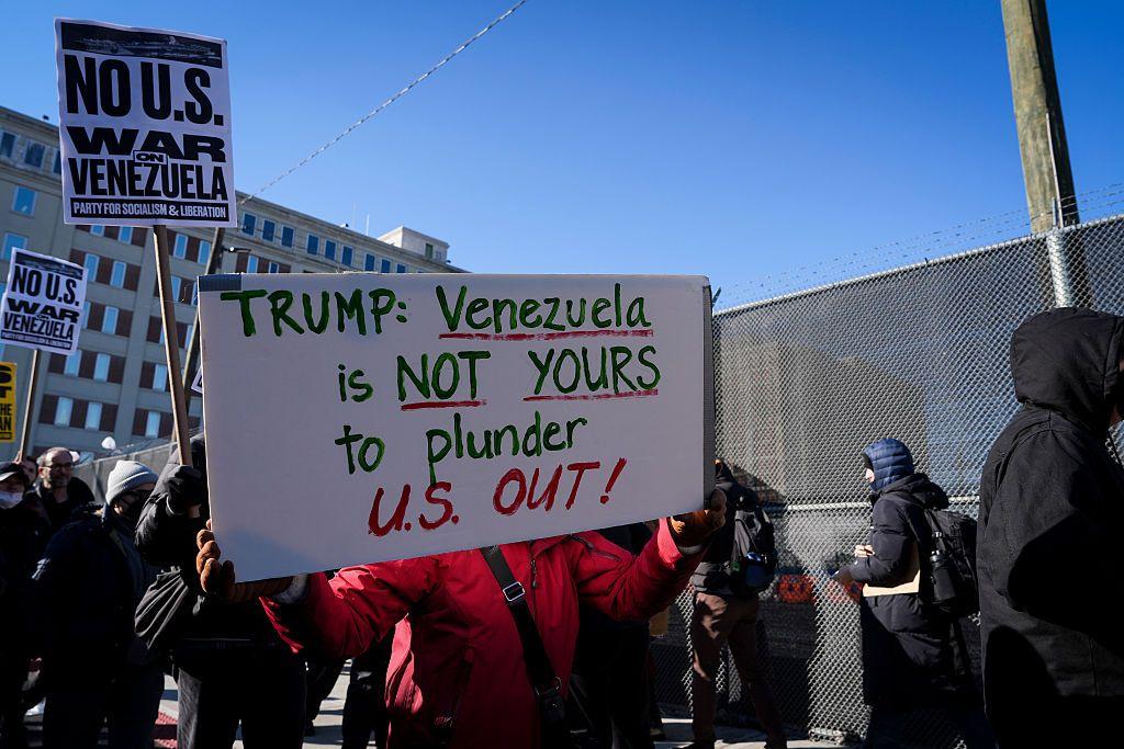 Una persona exhibe un cartel que dice en inglés: "Trump, Venezuela no es para que tú la saquees". 