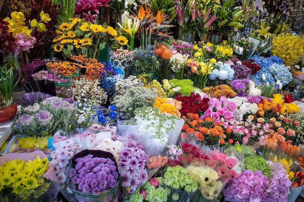 Muchas flores distintas en puesto de venta.