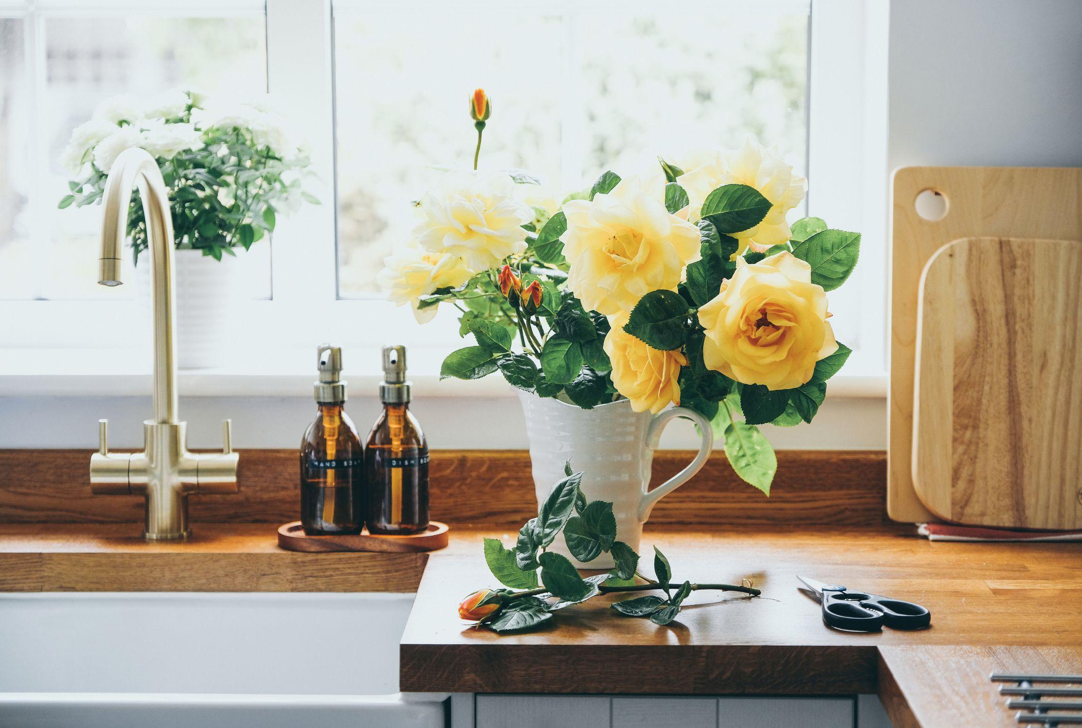 Un florero con rosas blancas y amarillas junto al fregadero de una cocina.
