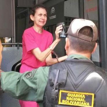 María Elena Uzcátegui, vestida de fucsia, en la época en la que estaba detenida en la cárcel de Uribana. Frente a ella hay un hombre de espalda con un chaleco que dice Guardia Nacional Bolivariana.