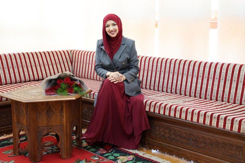 Žena sa maramom na glavi sedi na trosedu