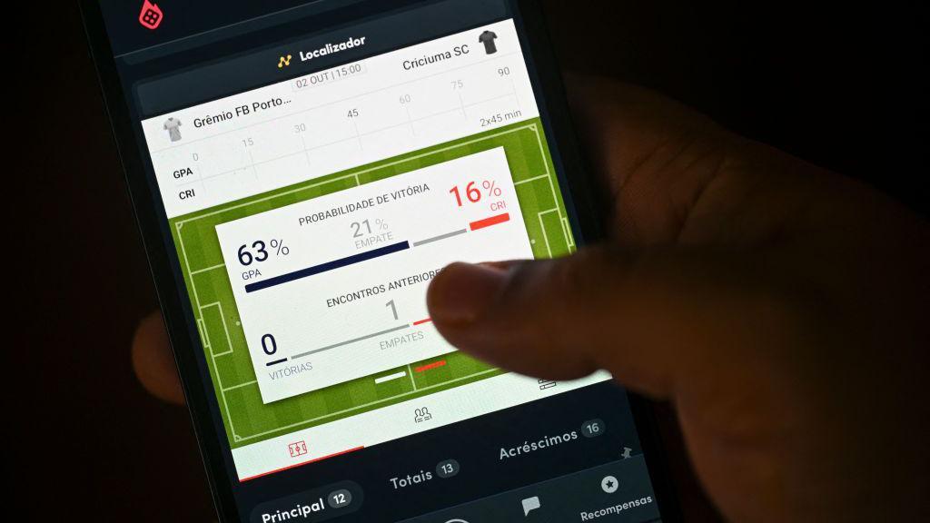M&atilde;o segurando celular com um site de apostas esportivas aberto na tela