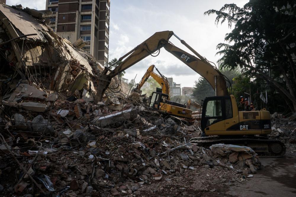Bulldóceres amarillos trabajando junto a los escombros de un edificio en Caracas.