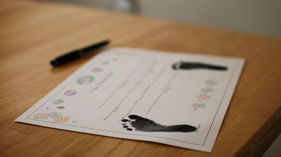 Certidão na mesa com pintura do pé de criança