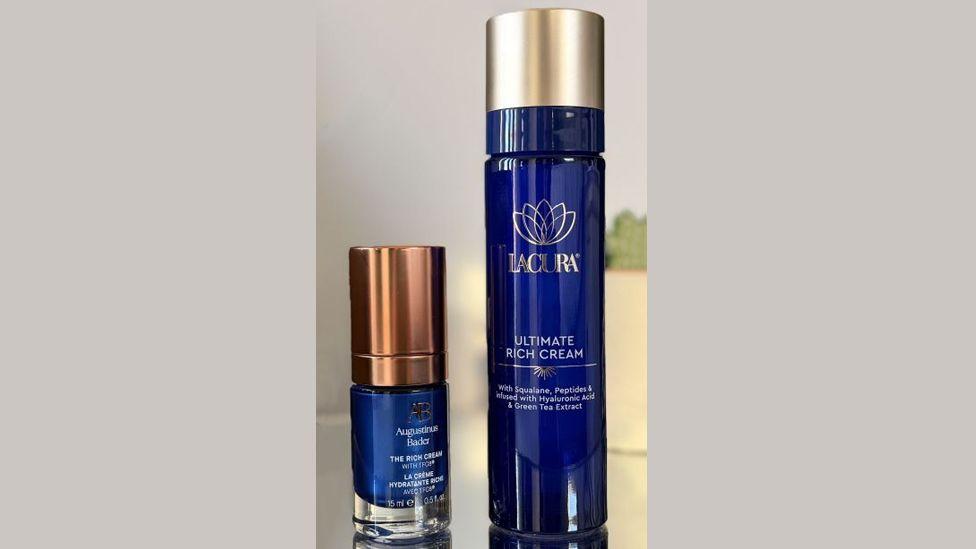 兩瓶深藍色的面霜擺放在桌上——一瓶是奧古斯丁·巴德（Augustinus Bader）的小容量產品，另一瓶是Lacura