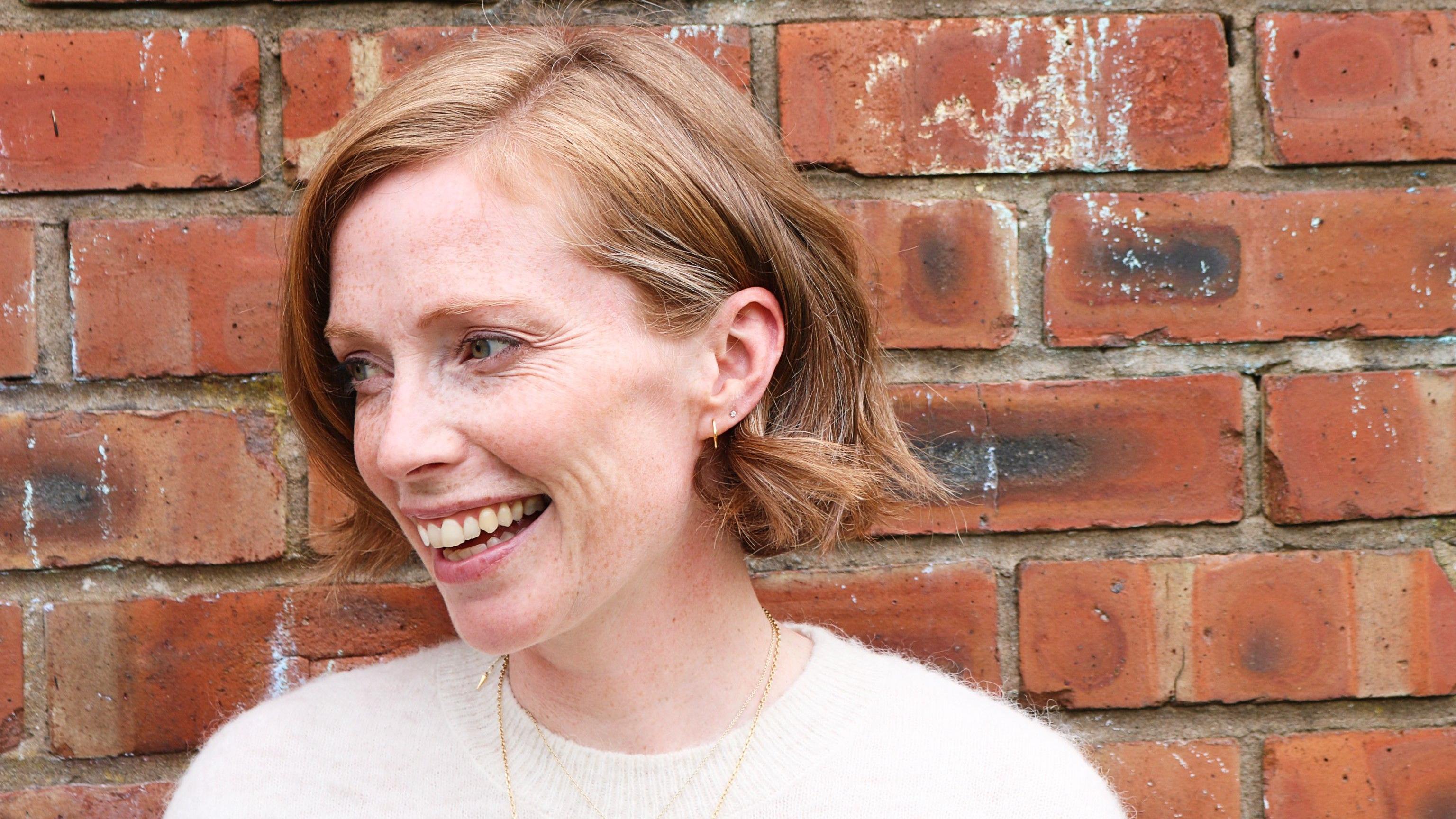 Mulher de cabelo curto sorri.