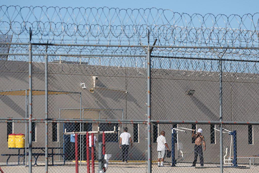 A través de las verjas y el alambre de concertina se ve a varios detenidos en el patio del centro de procesamiento del ICE en Adelanto, California, Estados Unidos, el 11 de julio de 2025. (Foto: PATRICK T. FALLON/AFP vía Getty Images)
