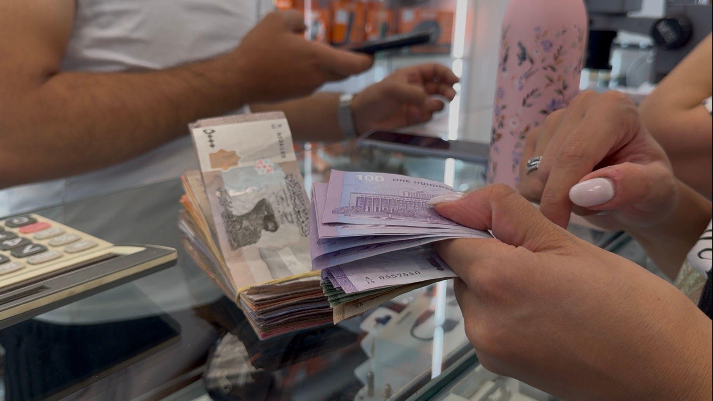 رجلان يُظهران رزمة من العملة السورية 